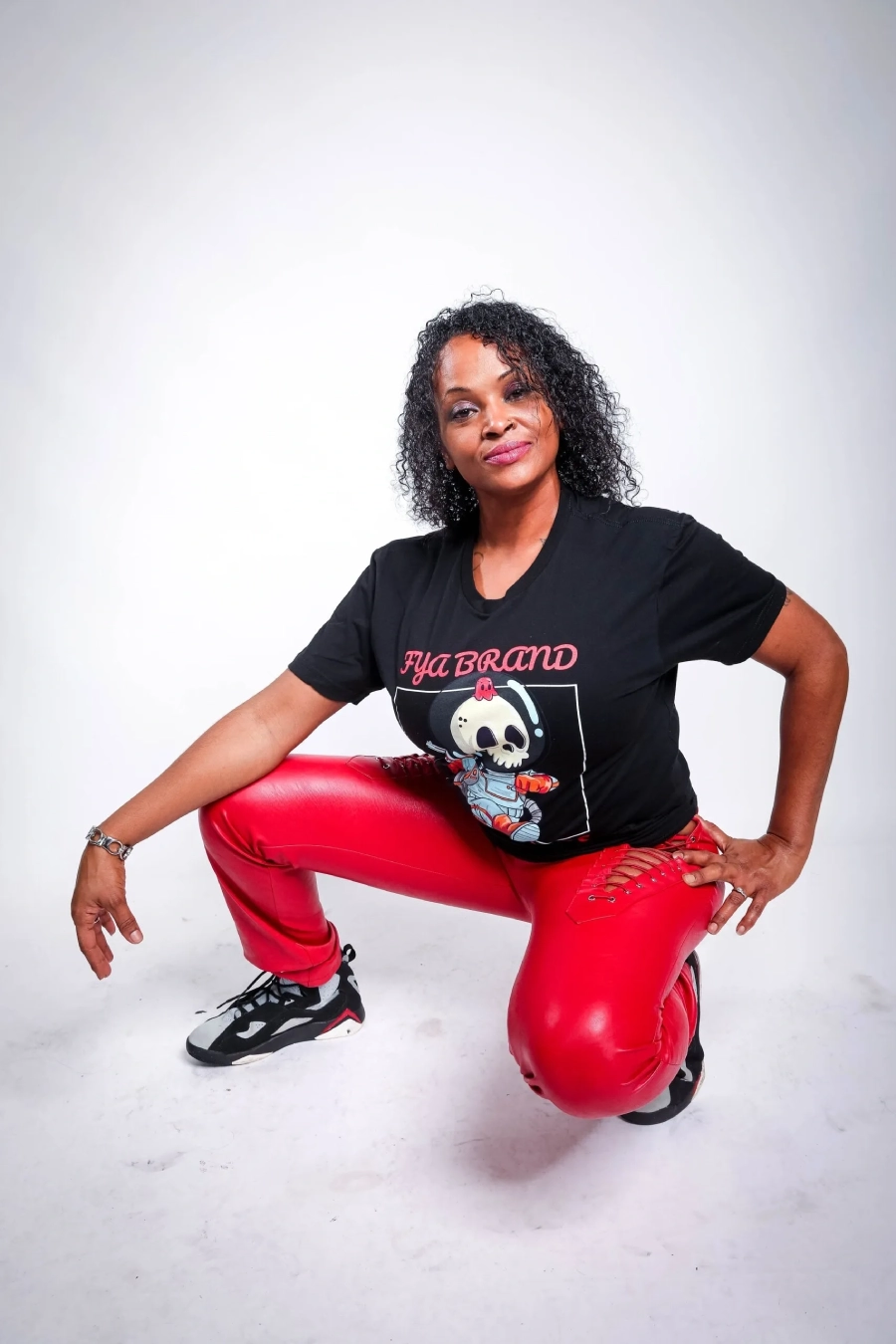 A woman squatting on the ground wearing red pants.