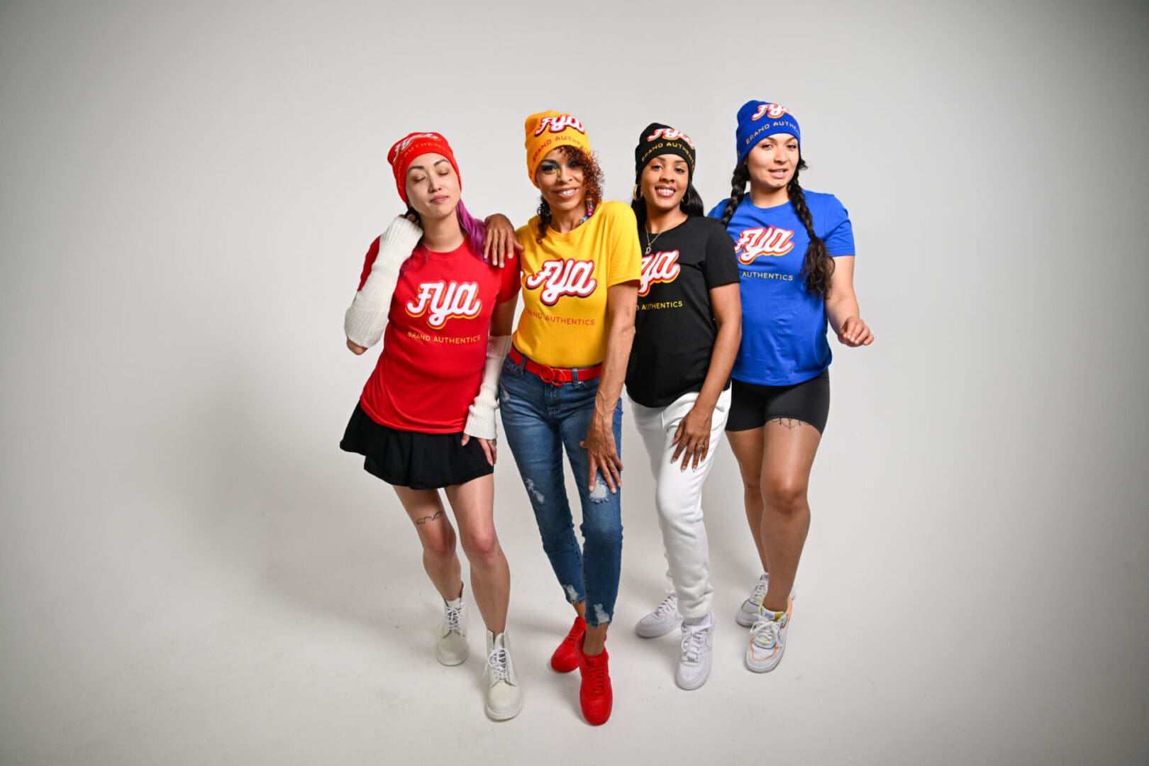 Four women posing in colorful casual outfits against a white background.